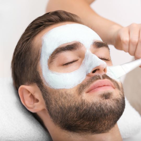 Mann mit Gesichtsmaske erhält eine Gesichtsbehandlung.