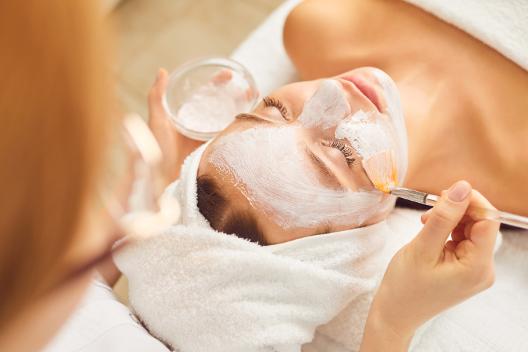 Frau mit Gesichtsmaske erhält eine Behandlung im Spa.